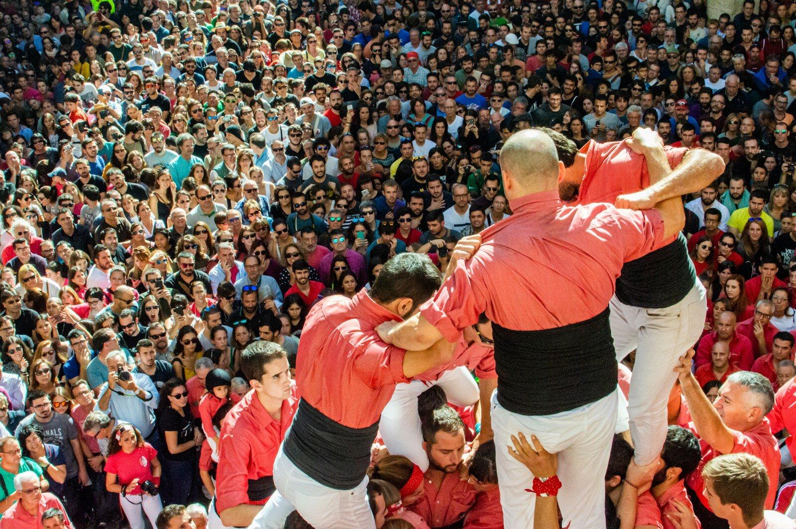 Castellers climbing above a tightly packed pinya
