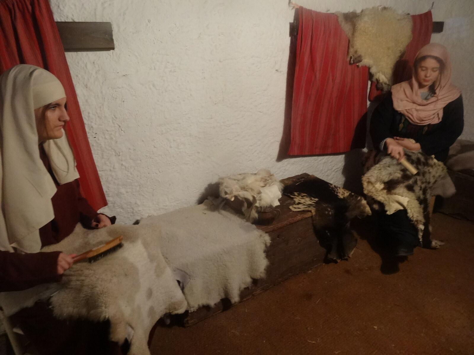 Two costumed volunteers working wool in an indoor traditional-trade tableau at Corbera de Llobregat
