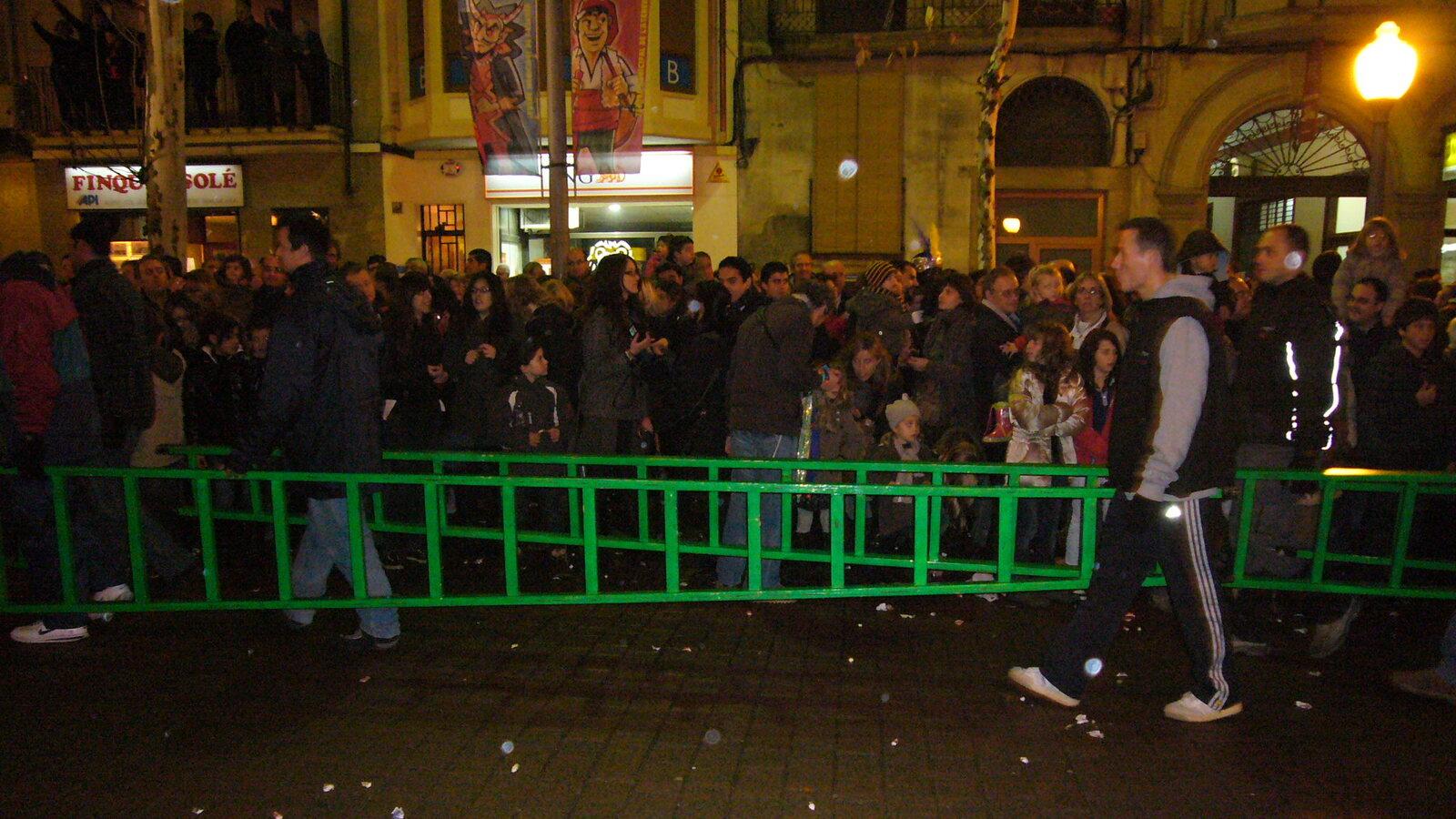 Pages carrying a long green gift-delivery ladder through the Three Kings crowd in Igualada
