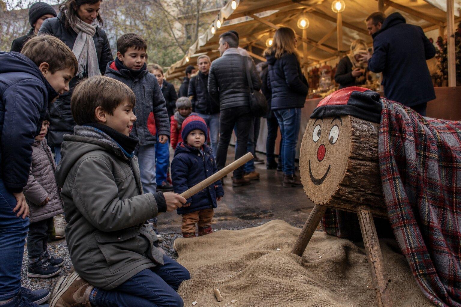 Children gathered around a community Tió at a Christmas fair