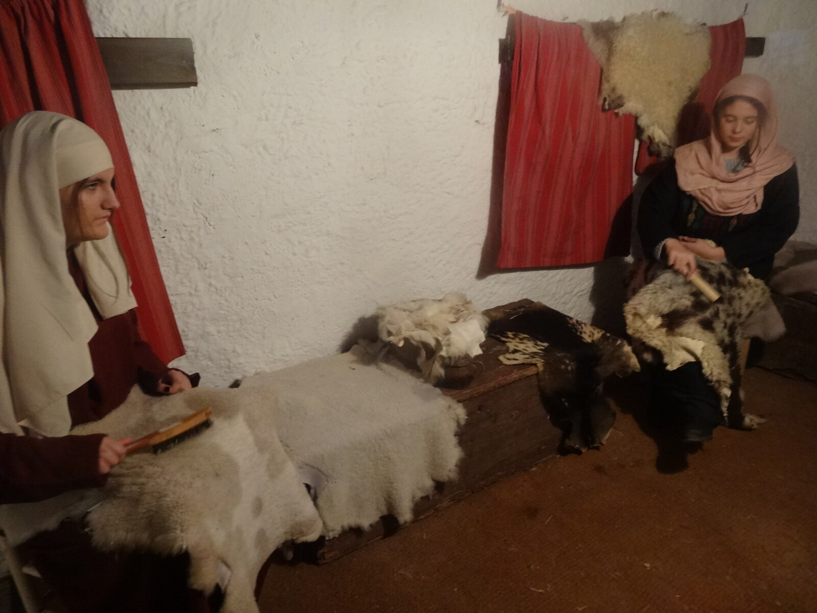 Two costumed volunteers working wool in an indoor traditional-trade tableau at Corbera de Llobregat